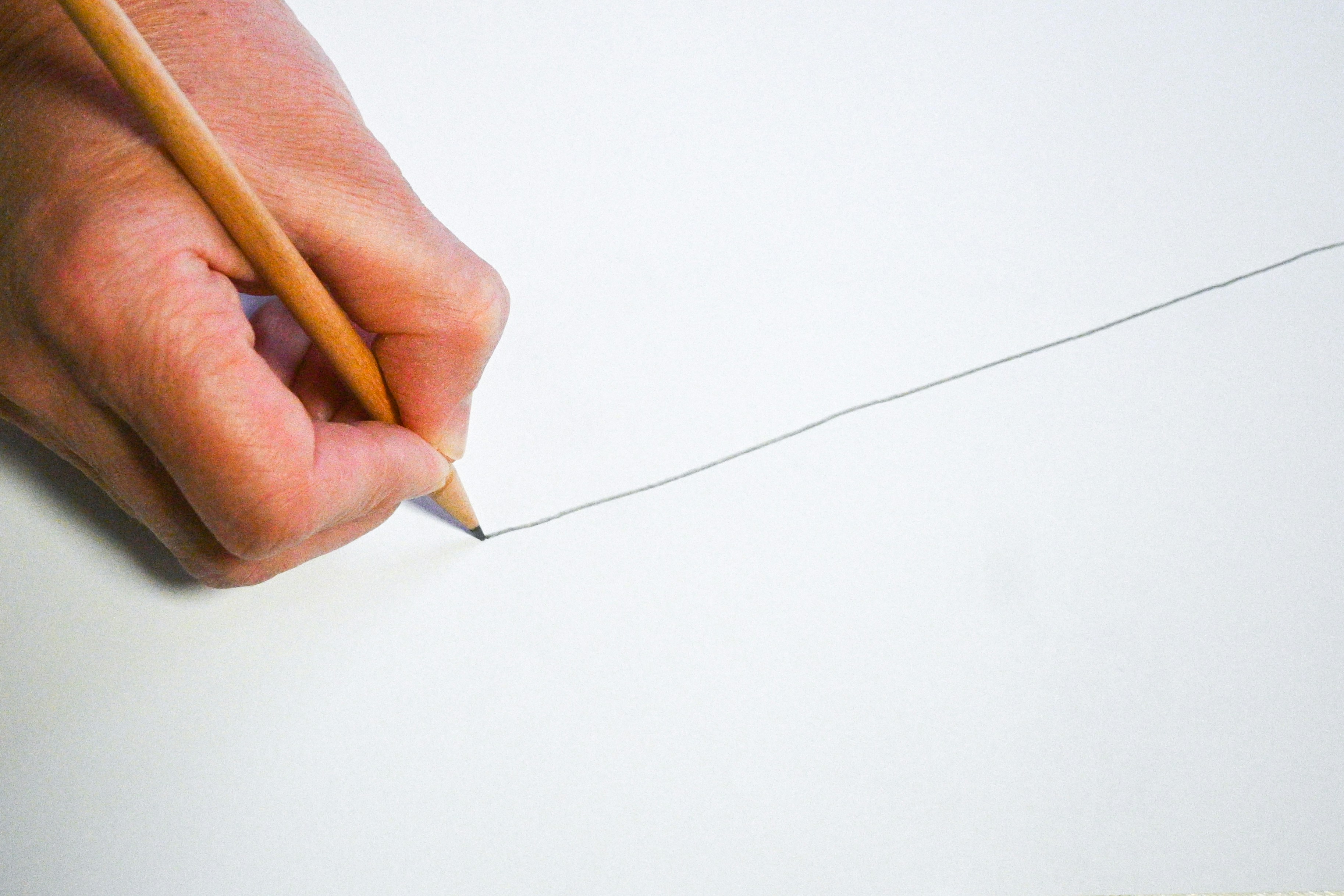 hand drawing a line on a piece of paper with a pencil